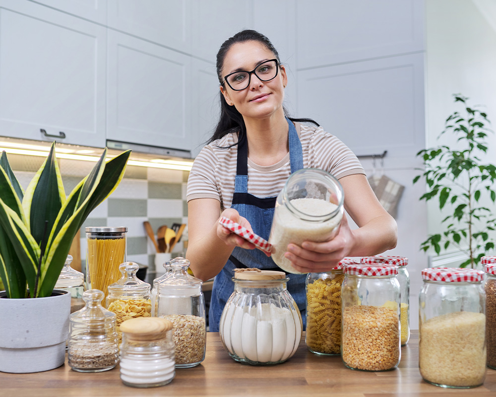 Eine Frau in der Küche zeigt Gläser zur Aufbewahrung von Trockenfutter