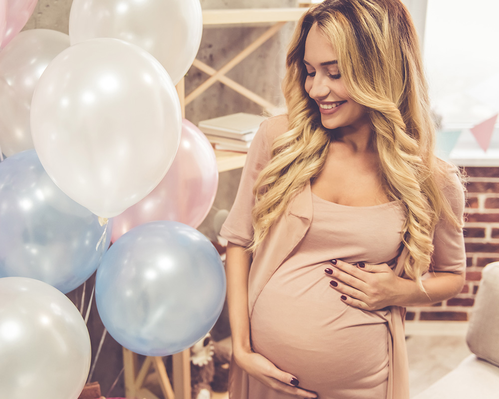 Eine schwangere Frau betrachtet mit einem Lächeln bunte Luftballons auf einer Baby-Shower-Party