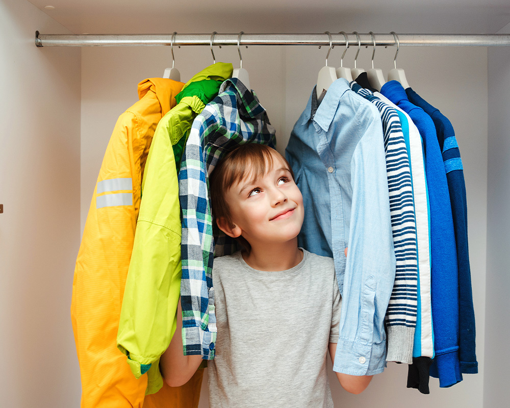Ein Junge in einem Schrank mit Kleidung
