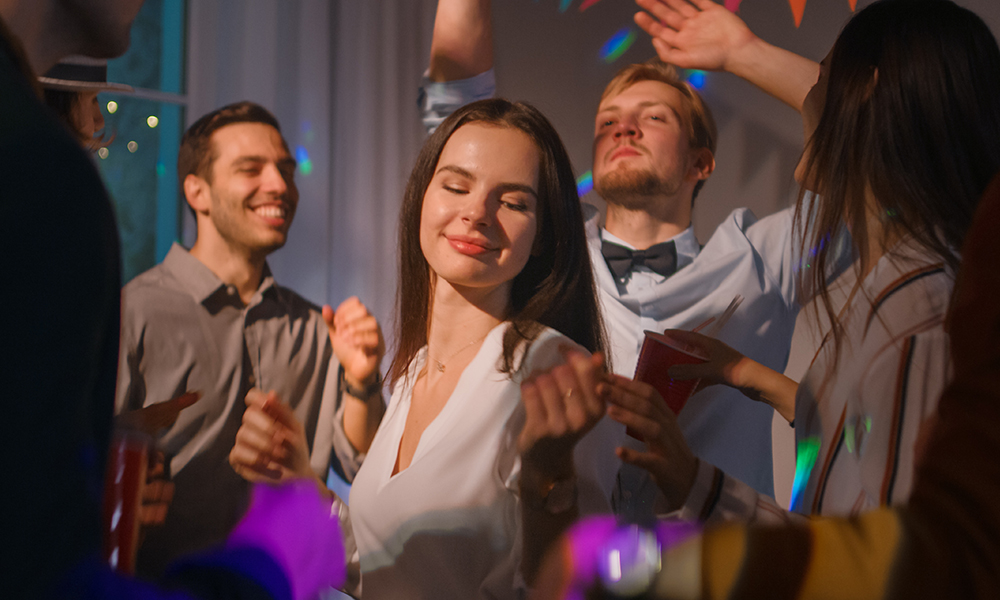 Eine Gruppe von Menschen, die auf einer Party tanzen, darunter eine Frau, die die Musik genießt.